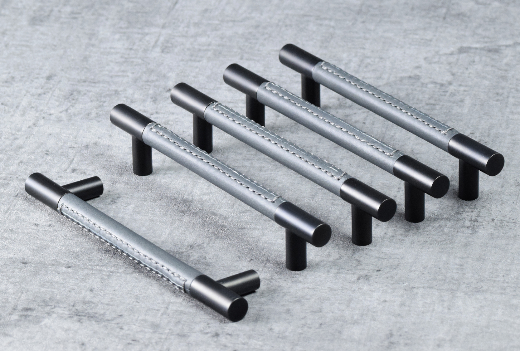 Image of five custom length recess leather barrel pull handles. One of the pull handle is positioned on the side. Grip of the pull handle is finished in slate grey leather. The end caps and legs are finished in matt black chrome.