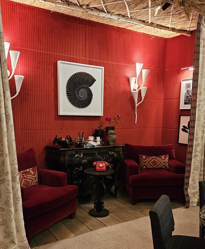 The dinning room designed by Joy Moyler has a vibrant red wall with a side room divided with drapes, perfect for an after dinner gossip