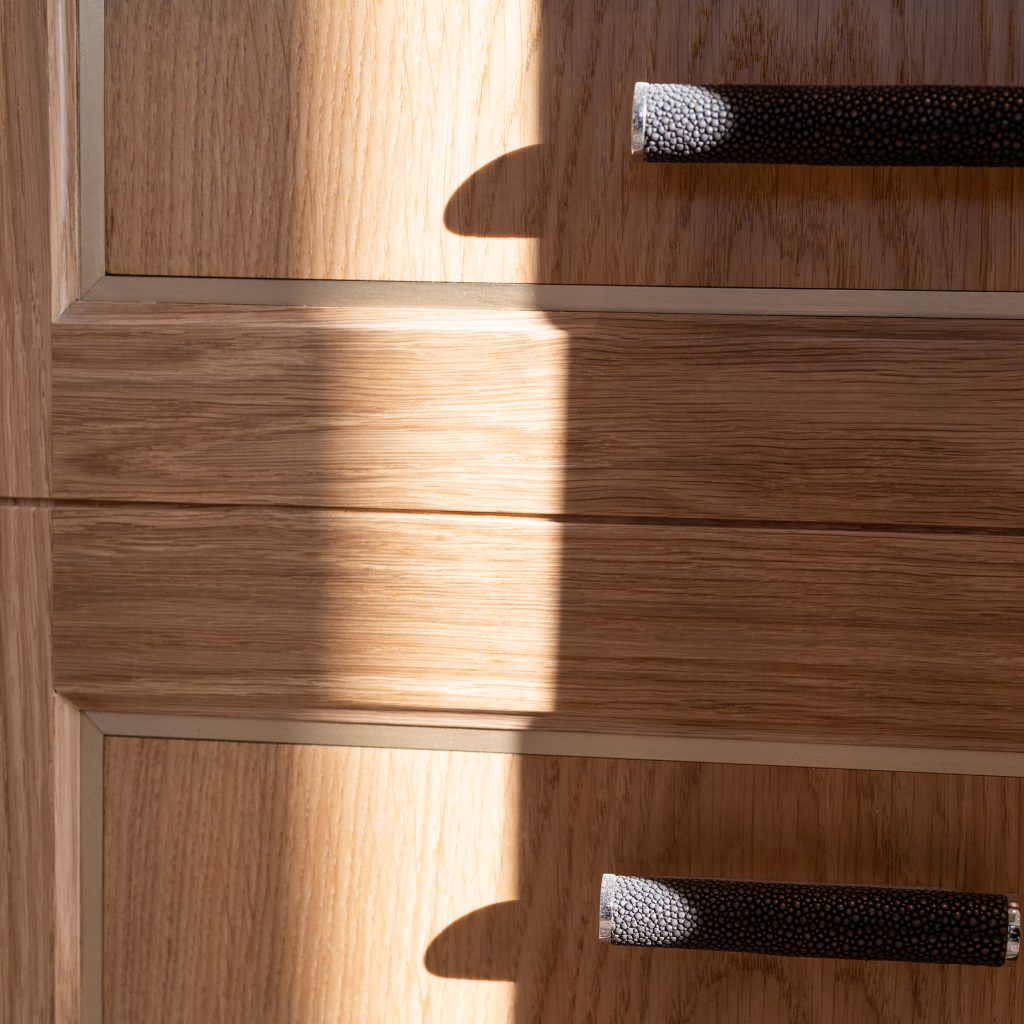 Two drawers with Shagreen scroll handles. The deep grey and polished nickel cabinet pulls contrast against the light oak material of the drawers.