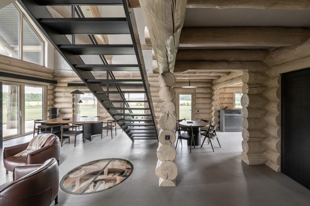 a living area in a log cabin style interior. This project called House of the Hunter is a mixture of wooden log walls, concreate floors and natural material details.