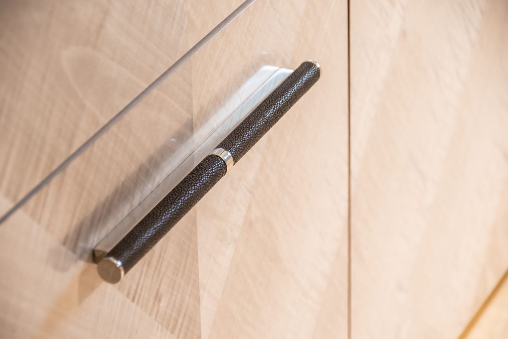Custom scroll cabinet handle fixed to a book end high gloss veneer. The handles have a shagreen grip made with Turnstyle Designs unique amalfine material. This trademark composite material gives a beauiful finish exactly like the real thing but in a more sustainable way.