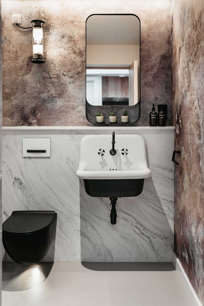 A luxury en-suite toilet and sink bathroom with decorative marble quarts walls in contrasting colours.