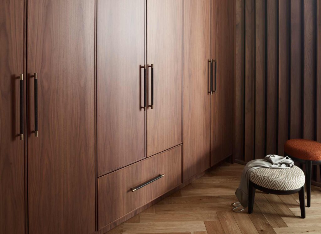 A large built in double wardrobe with lower drawers. Shagreen inspired Amalfine cabinet pulls Turnstyle Designs are used in a dark leather and fine antique brass finish to match the dark wooden bespoke wardrobes.