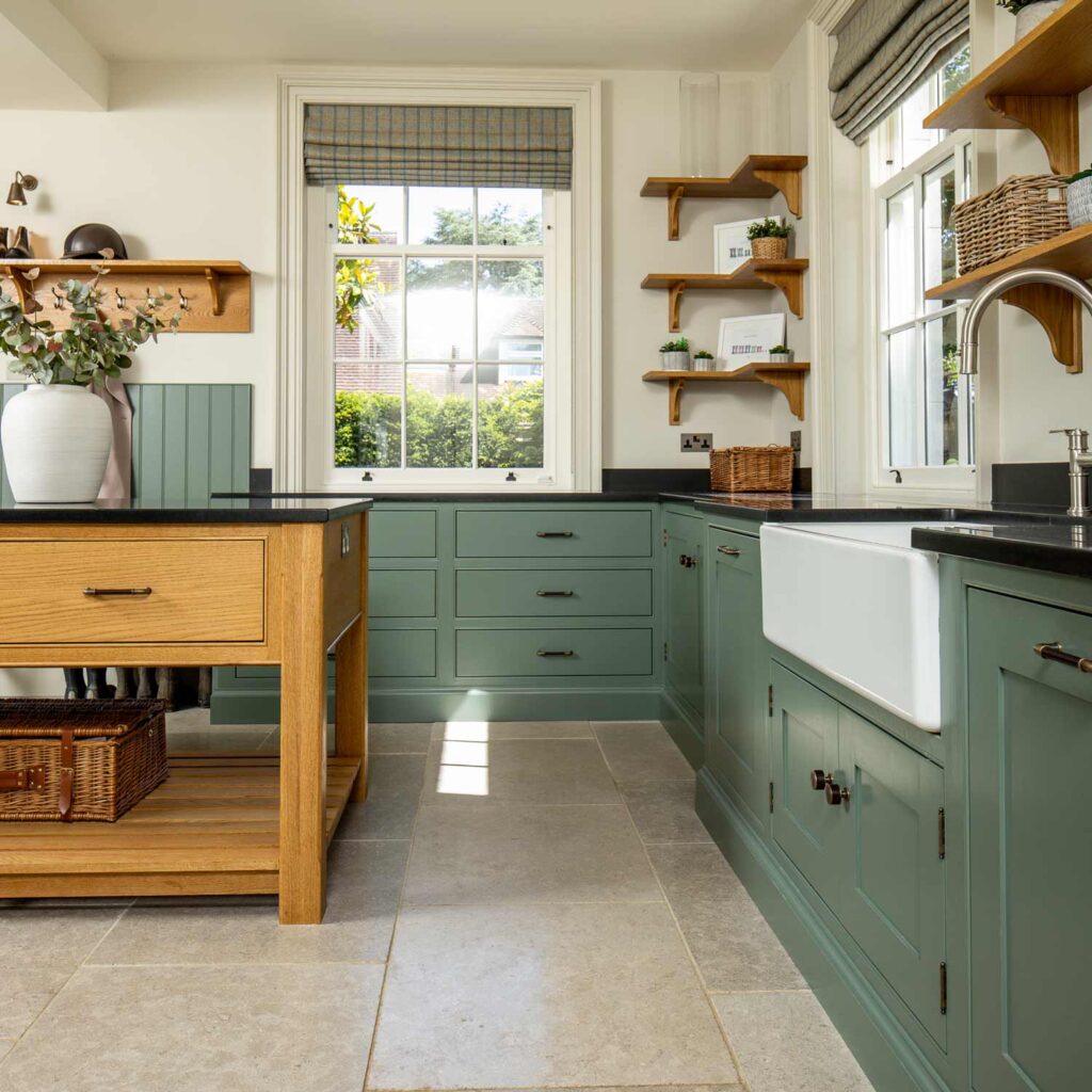Large boot room with bespoke oak wooden island. Farrow and ball green smoke painted bespoke cabinetry made by Maple and Gray.