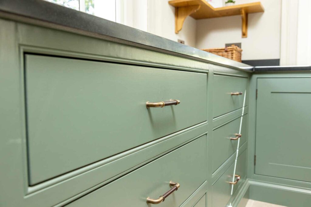 Handmade leather hardware by Turnstyle Design have been used on these bespoke drawers in a spacious boot room. The handles are Chocolate brown leather alongside a Fine Antique Bras metal finish. The drawers and units are in Farrow and Ball Green Smoke colour.