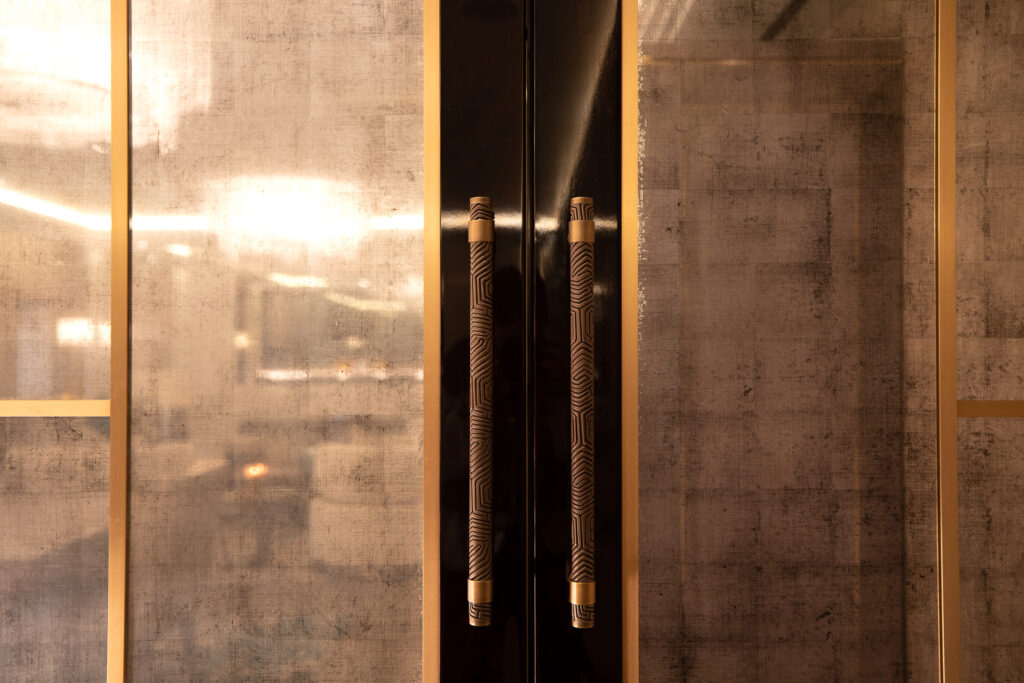 two statement pull handles on luxury glass double doors in high end Mayfair apartment. The door pulls are handmade by Turnstyle Designs.