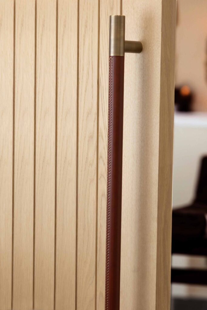 Large hand stitched leather door pull but Turnstyle Designs shown on light oak door leading to luxury spa treatment room.