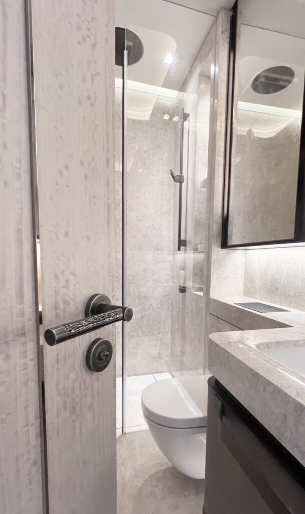 Hand hammered brass door lever shown on a high end door leading to a luxury bathroom. The Door lever and matching hardware is made by Turnstyle Designs.