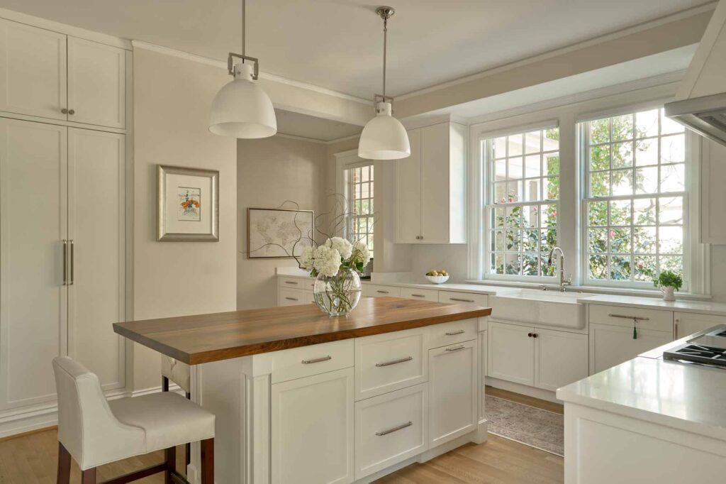 A luxury large kitchen with central island, kitchen is a light oatmeal colour with deep walnut counter tops. Textured Shagreen inspired handles have been used on the doors and drawers throughout the kitchen in a Sand and Polished Nickel brass finish. These handles are handmade by Turnstyle Designs.