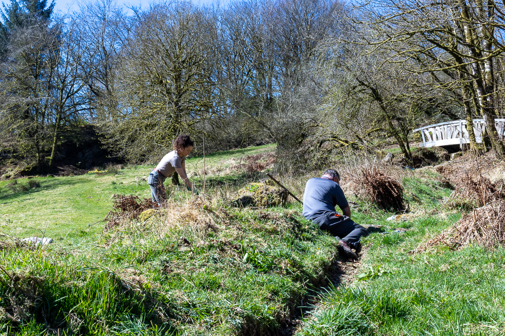 Volunteers help to clear a gully of debris and weeds. The gully directs the water to a small stream that runs around the garden and Ashcombe estate.