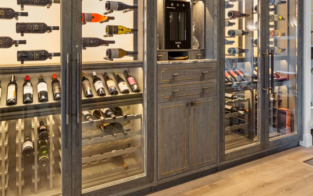 Luxury home wine cellar with custom glass-front cabinets, backlit wine storage, and dark wood cabinetry with Woven amalfine handmade handles by Turnstyle Designs.