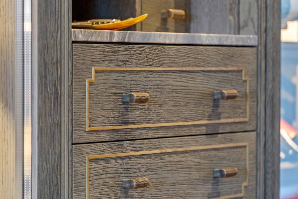 Luxury wine storage drawers with Woven recess amalfine cabinet t bar handle detailing. The t bar handles are finished in a silver bronze and fine antique brass to match the dark oak wood finish.