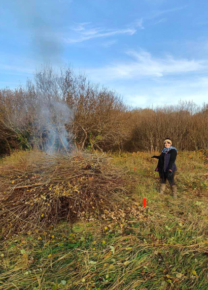 ND Coast Nationla Landscape – Braunton Burrows Volunteer day (1) lady with arms out showing a bonfire with smoke appearing